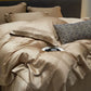Beige bedding set with a linear patterned pillow on a bed.